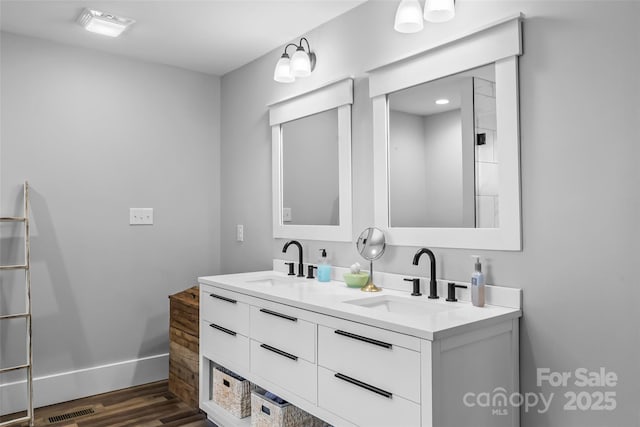 full bath featuring double vanity, visible vents, a sink, and wood finished floors