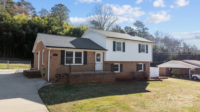 split level home featuring a front yard, a chimney, and brick siding