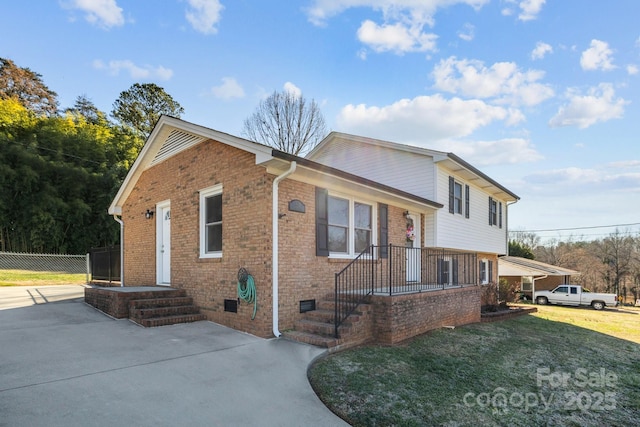 view of front of house with a front yard, crawl space, brick siding, and fence