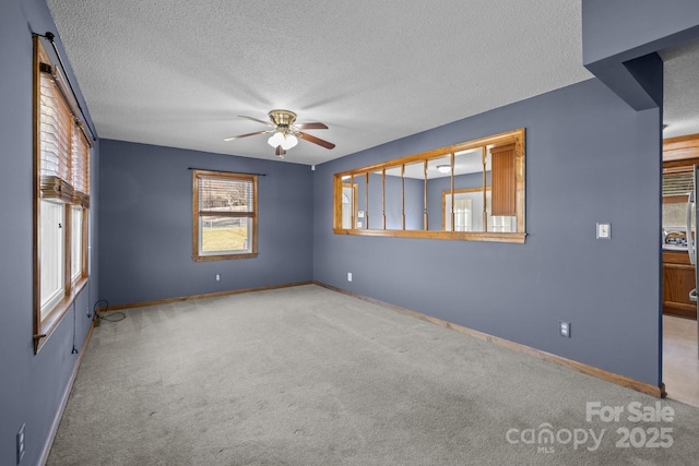 unfurnished room with a ceiling fan, carpet flooring, a textured ceiling, and baseboards