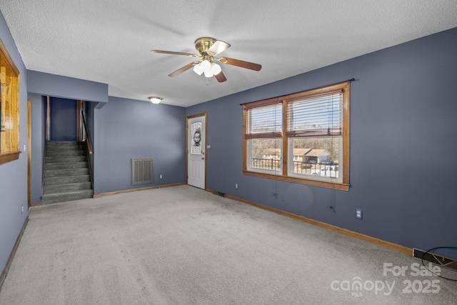 empty room featuring baseboards, stairs, visible vents, and a textured ceiling