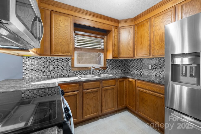 kitchen featuring appliances with stainless steel finishes, brown cabinetry, a sink, and decorative backsplash