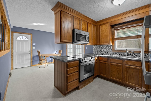 kitchen with stainless steel appliances, brown cabinets, a sink, and light floors