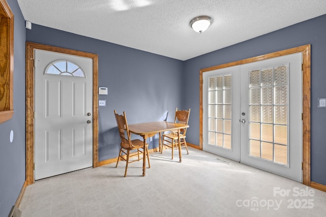 dining area featuring french doors, plenty of natural light, a textured ceiling, and baseboards