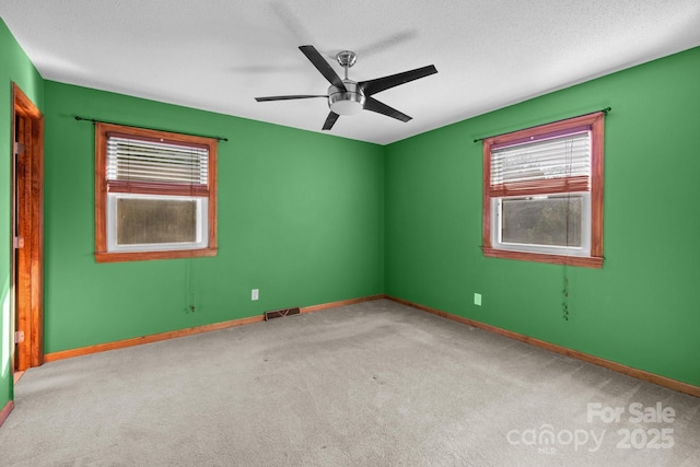 carpeted spare room with a textured ceiling, ceiling fan, visible vents, and baseboards