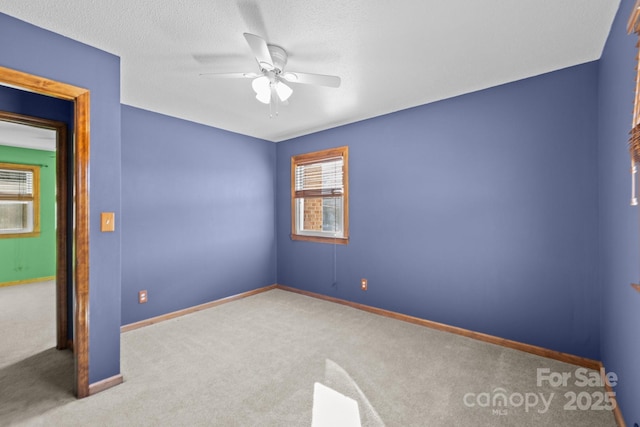 empty room featuring ceiling fan, a textured ceiling, carpet flooring, and baseboards