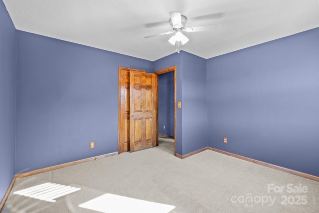 empty room with ceiling fan, carpet, and baseboards