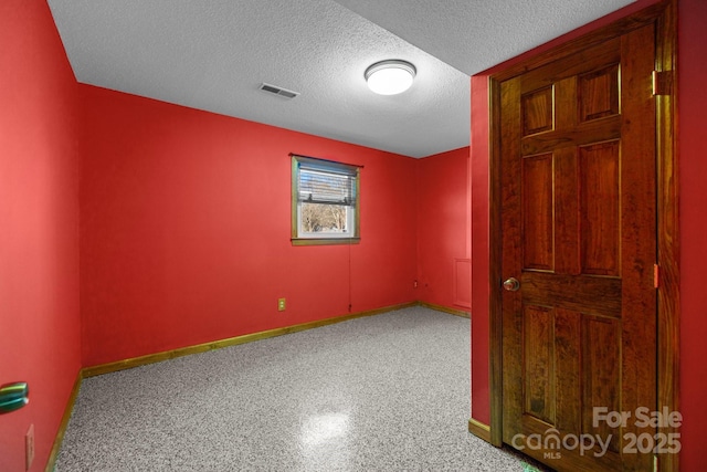 empty room featuring visible vents, a textured ceiling, and baseboards