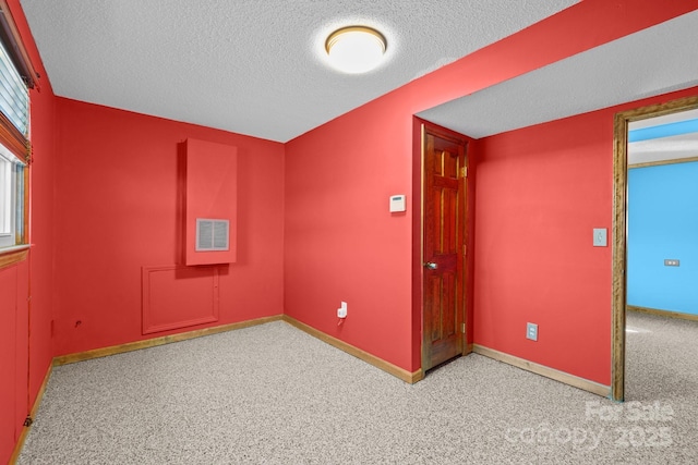 carpeted empty room featuring visible vents, a textured ceiling, and baseboards