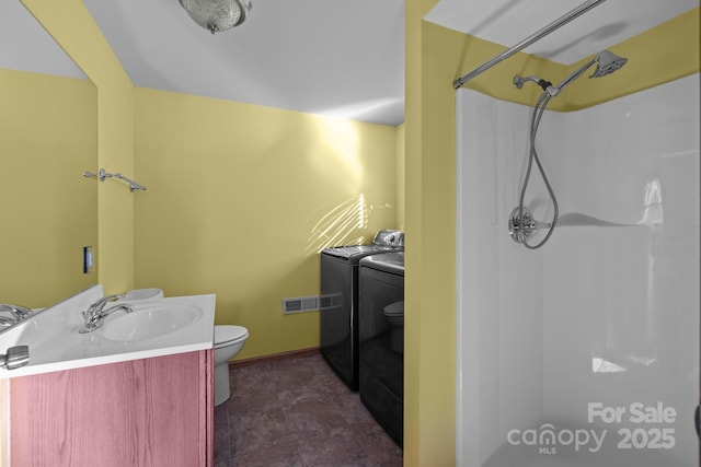 bathroom with visible vents, a shower, toilet, vanity, and separate washer and dryer