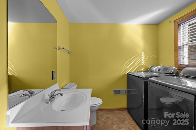 washroom featuring a sink, laundry area, washing machine and clothes dryer, and visible vents