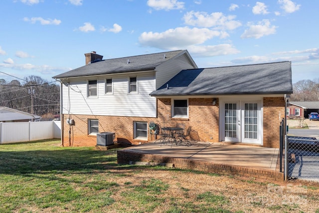 back of property with a yard, french doors, fence, and brick siding