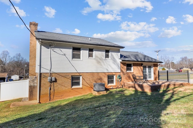 rear view of property featuring brick siding, a chimney, central air condition unit, a lawn, and fence