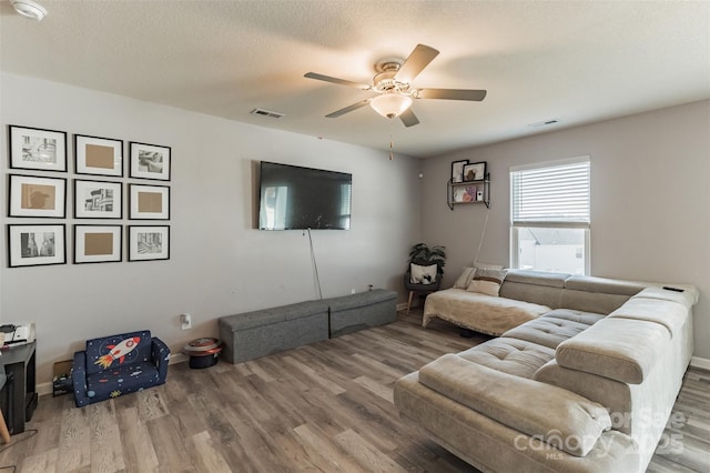 living area with visible vents, ceiling fan, a textured ceiling, and wood finished floors