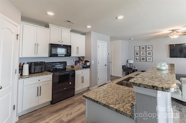 kitchen featuring visible vents, white cabinets, a sink, light wood-type flooring, and black appliances