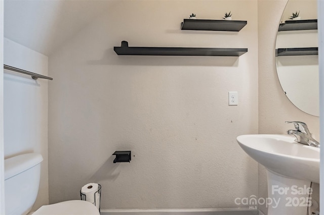 half bath with lofted ceiling and toilet