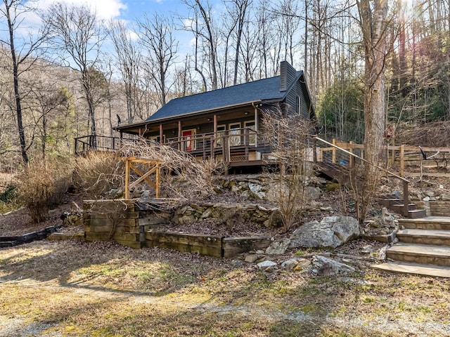 exterior space featuring stairway, a chimney, and a shingled roof