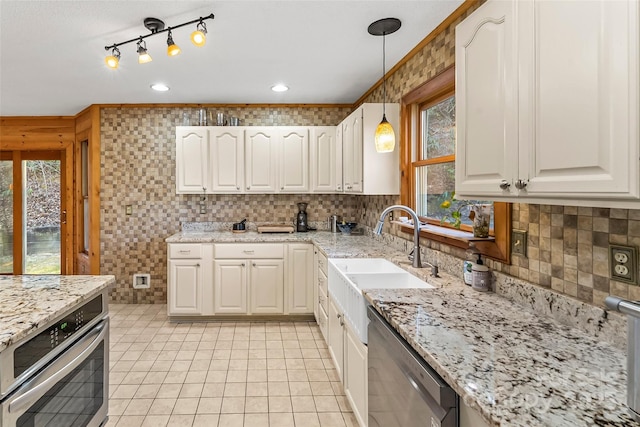 kitchen with a sink, light stone counters, backsplash, stainless steel appliances, and hanging light fixtures