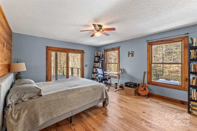 bedroom with baseboards, a textured ceiling, light wood-style flooring, and access to outside