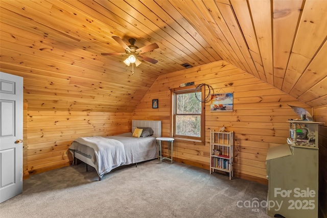 carpeted bedroom featuring lofted ceiling, wood walls, wooden ceiling, and ceiling fan