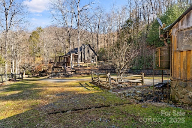 view of yard featuring a vegetable garden, a view of trees, and fence