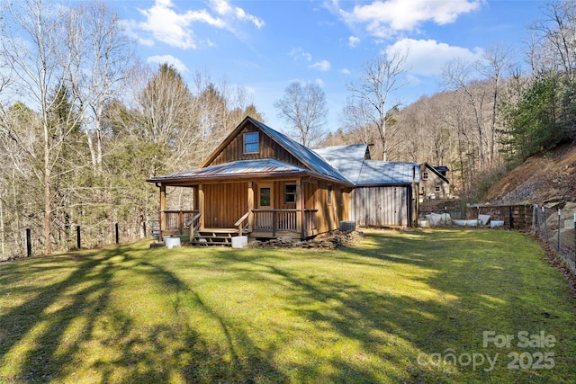 rear view of property featuring metal roof, a yard, and fence