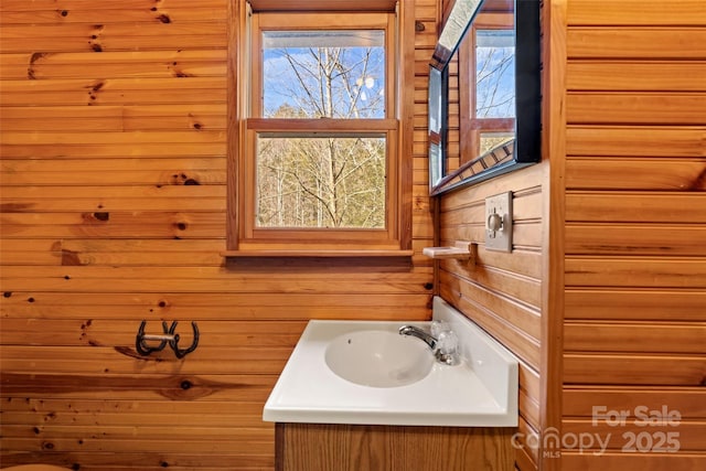 bathroom featuring plenty of natural light, wood walls, and vanity