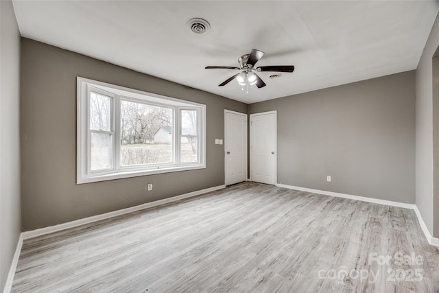 unfurnished room with baseboards, visible vents, ceiling fan, and wood finished floors