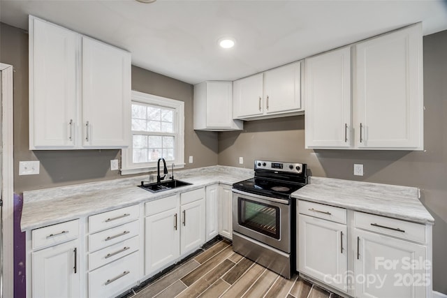 kitchen featuring wood tiled floor, white cabinets, a sink, and stainless steel electric range