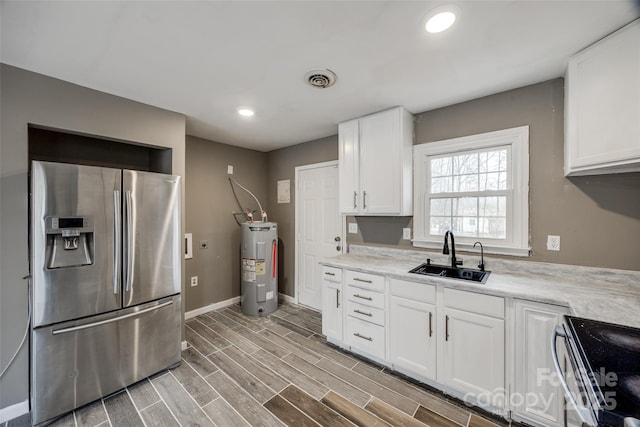 kitchen with electric water heater, stainless steel appliances, a sink, light countertops, and wood tiled floor