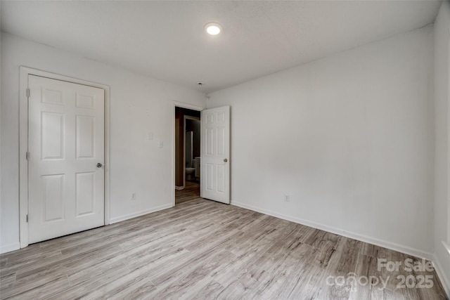 spare room with baseboards and light wood-style floors