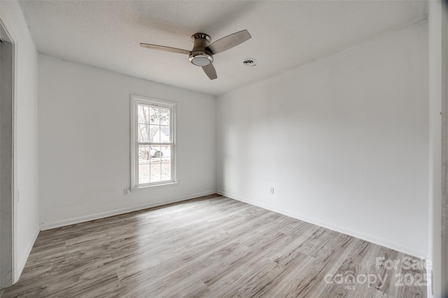 unfurnished room with ceiling fan, a textured ceiling, baseboards, and wood finished floors