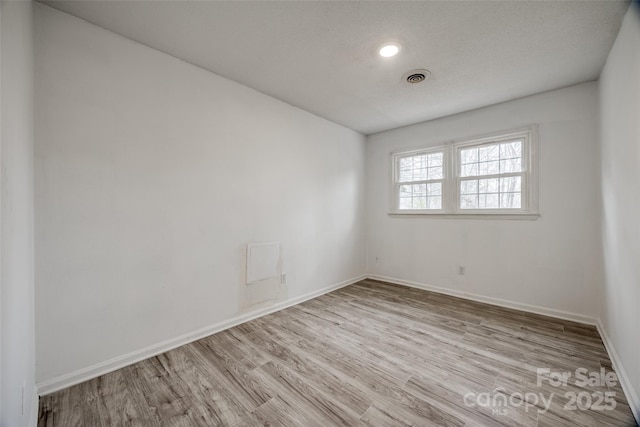 empty room with visible vents, baseboards, and wood finished floors