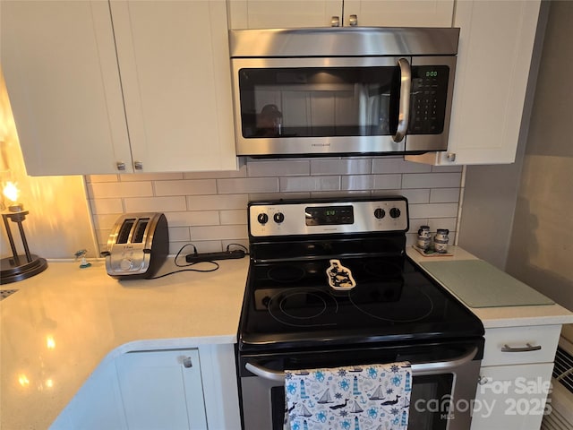 kitchen with stainless steel appliances, white cabinets, light countertops, and decorative backsplash