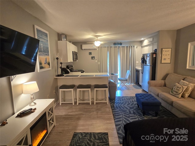 living area featuring dark wood-style floors, a ceiling fan, a textured ceiling, and a wall mounted AC