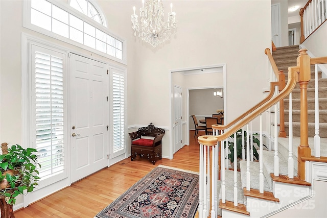 entryway with a chandelier, stairway, a towering ceiling, and wood finished floors