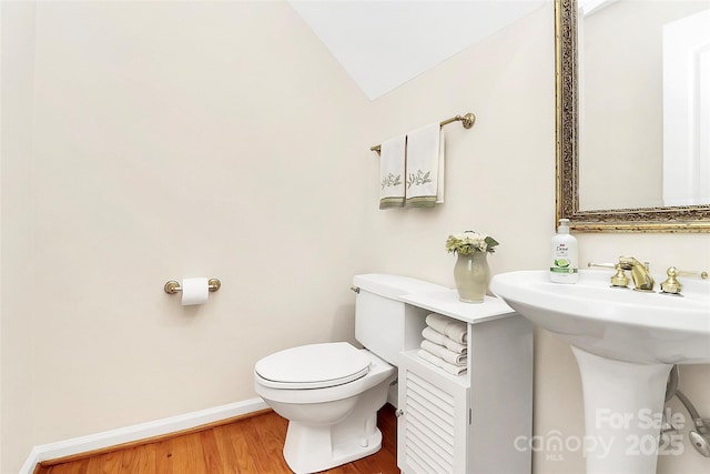 bathroom with baseboards, toilet, wood finished floors, and vaulted ceiling