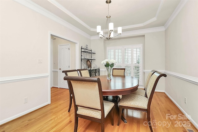 dining space with light wood-type flooring, visible vents, an inviting chandelier, crown molding, and baseboards