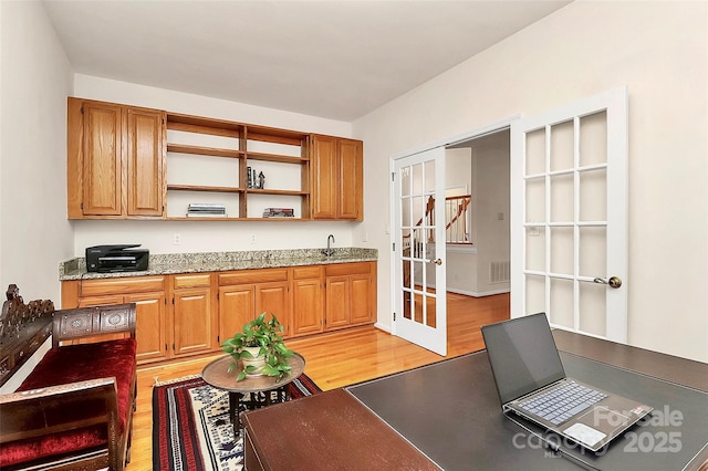 kitchen with light wood-style flooring, french doors, light stone countertops, and open shelves