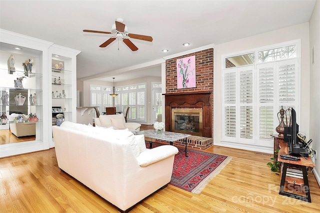 living area with light wood-style flooring, recessed lighting, a fireplace, and ceiling fan