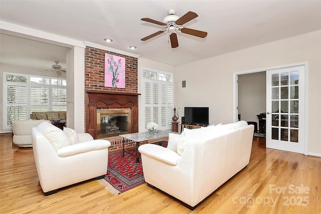 living room featuring a brick fireplace, light wood-style flooring, recessed lighting, and ceiling fan