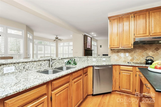 kitchen featuring a sink, light stone counters, stainless steel dishwasher, and under cabinet range hood