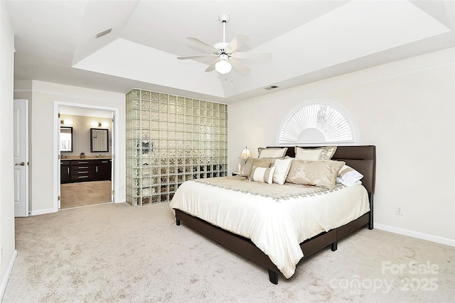 bedroom with a tray ceiling, carpet flooring, baseboards, and connected bathroom