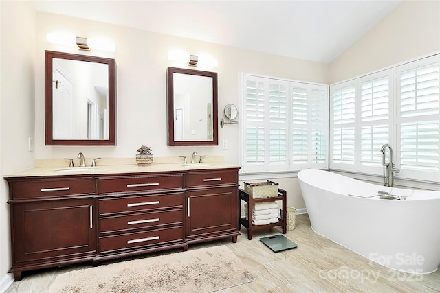 full bathroom featuring a freestanding bath, vaulted ceiling, double vanity, and a sink