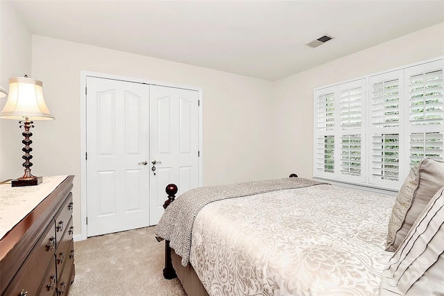 bedroom featuring a closet, visible vents, and light colored carpet