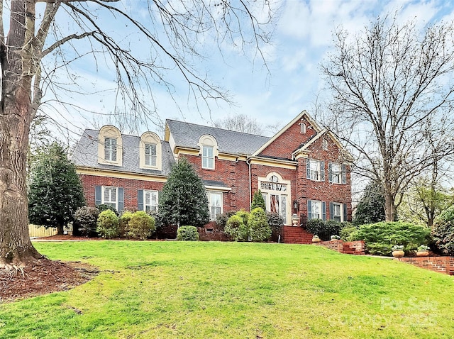 view of front facade with brick siding and a front yard