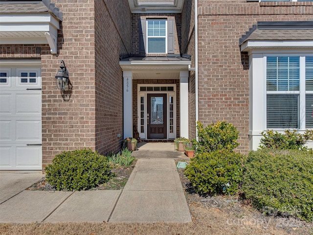 view of exterior entry with a garage and brick siding