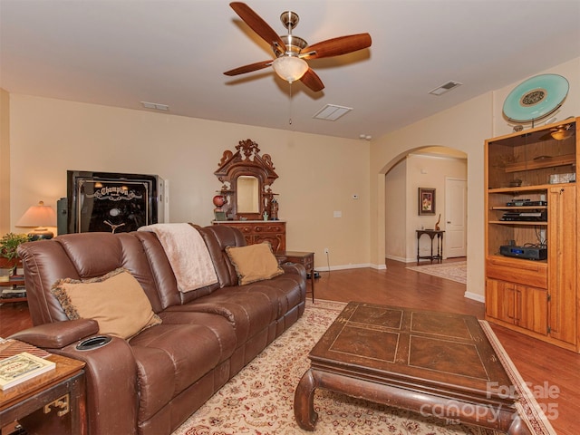 living room with visible vents, arched walkways, and wood finished floors