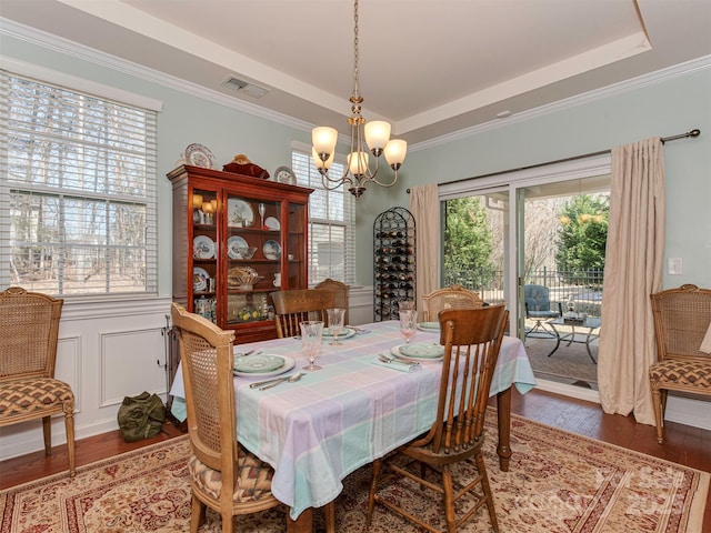 dining space with plenty of natural light, visible vents, a tray ceiling, and wood finished floors