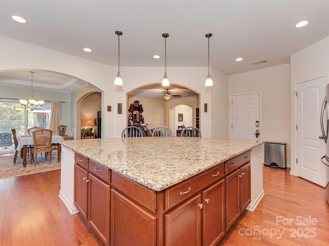 kitchen featuring light wood-style flooring, a center island, light stone counters, and recessed lighting